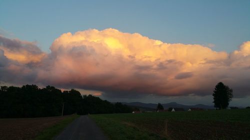 Panoramic view of road amidst field against sky during sunset