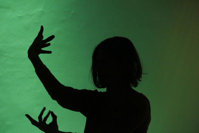 Silhouette woman dancing against wall