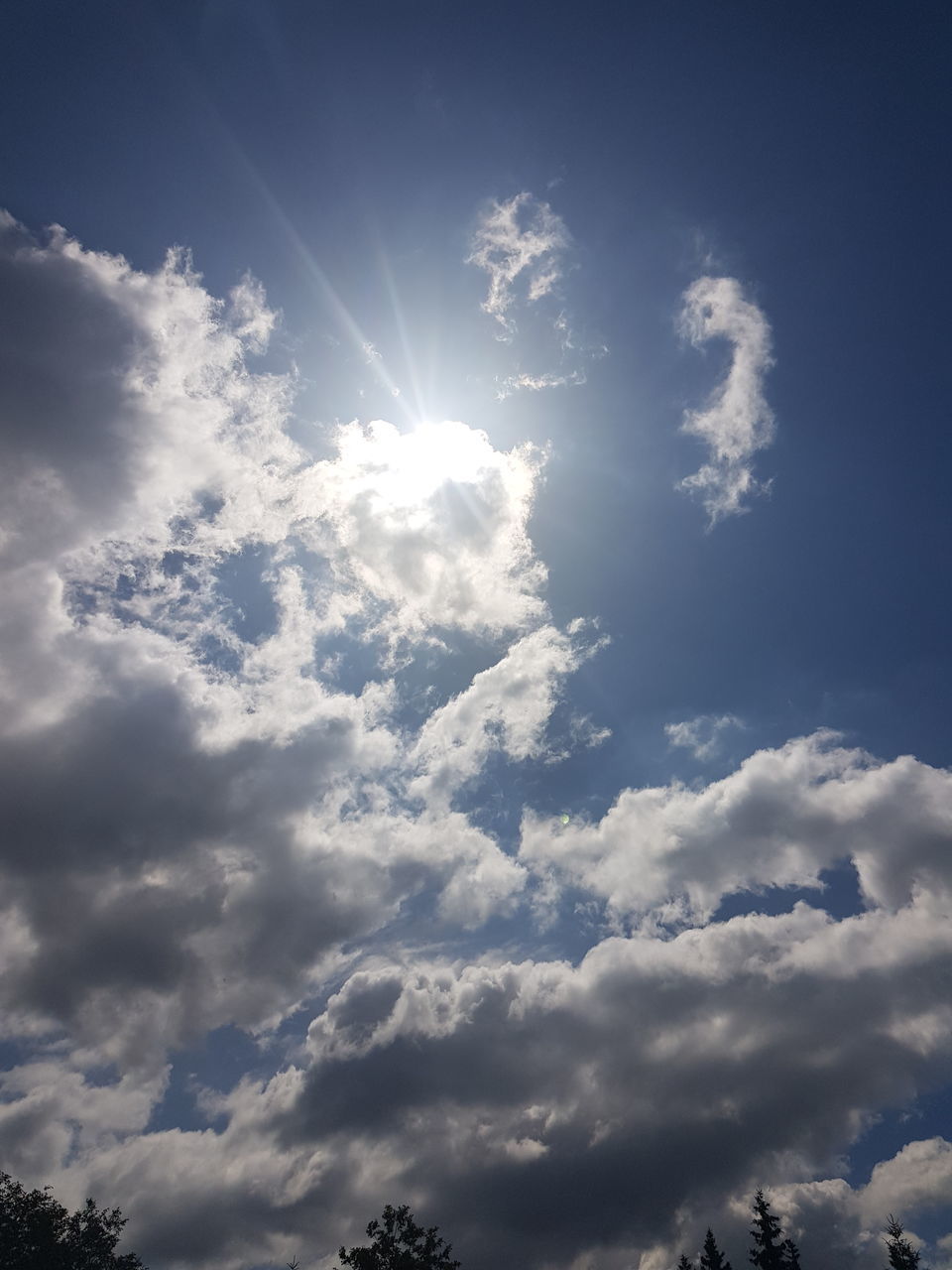 LOW ANGLE VIEW OF SUNLIGHT STREAMING THROUGH CLOUDS IN SKY