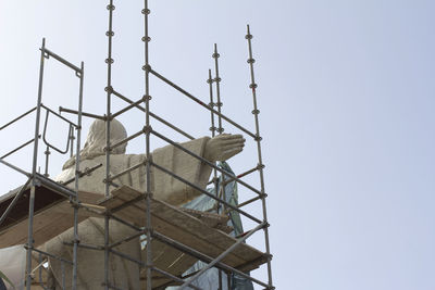 Low angle view of bird perching on metal structure against sky