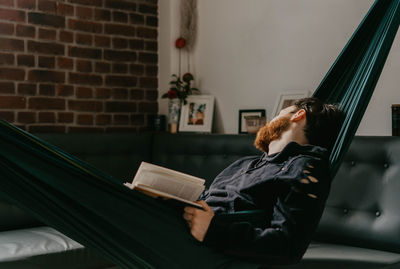 Man sitting on book against wall at home