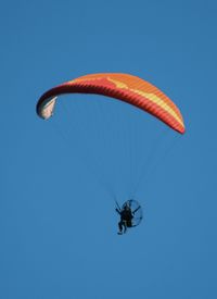 Low angle view of person paragliding against clear blue sky