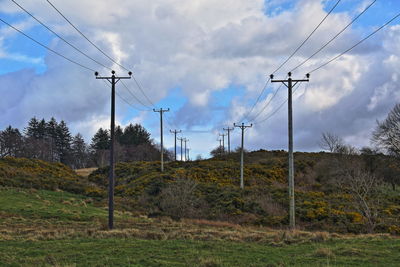 Low angle view of electricity pylon on field against sky