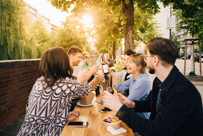 Male and female friends toasting while sitting at social gathering