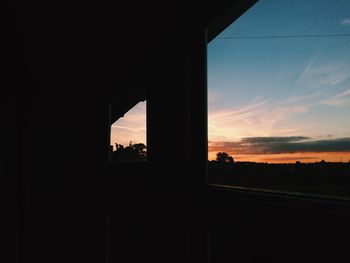 Silhouette trees against sky seen through window