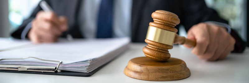 Midsection of man holding gavel on table