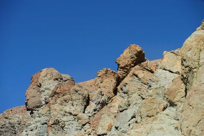 Low angle view of rocks against blue sky