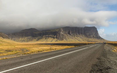 Empty road by mountains against sky