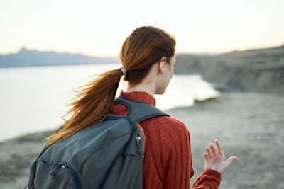 Rear view of woman standing by sea against sky