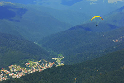 High angle view of person paragliding above green mountains