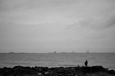 Men on rocks fishing in sea