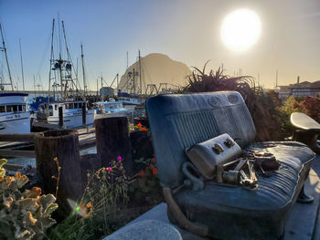 Sailboats moored at harbor against sky during sunset