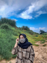 Portrait of man standing on field against sky