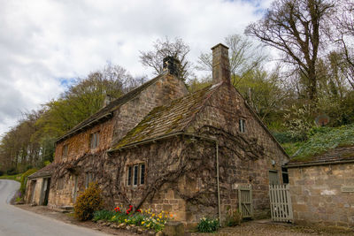 Old abandoned building by road against cloudy sky