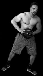 Portrait of young man standing against black background