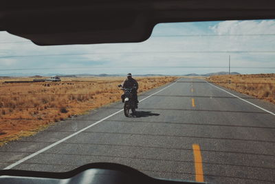 Man riding motorcycle seen through car