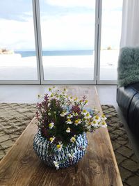 Close-up of flowers on table by window