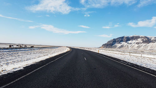Road by mountain against sky
