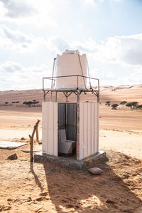 Lifeguard hut on desert land against sky