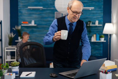 Side view of man using mobile phone while sitting on table