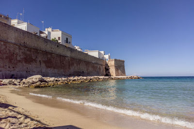 Buildings by sea against clear sky