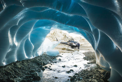 Helicopter landed just outside the entrance of a glacier cave.