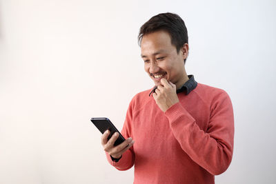 Mid adult man using smart phone against white background