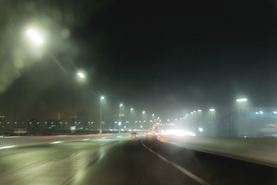 Road passing through illuminated city at night