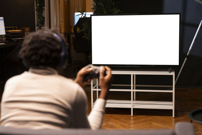 Rear view of woman using laptop at home