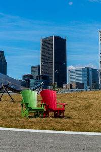 Chairs and tables in park against buildings in city