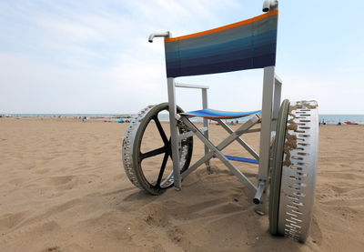 Deck chairs on beach against sky