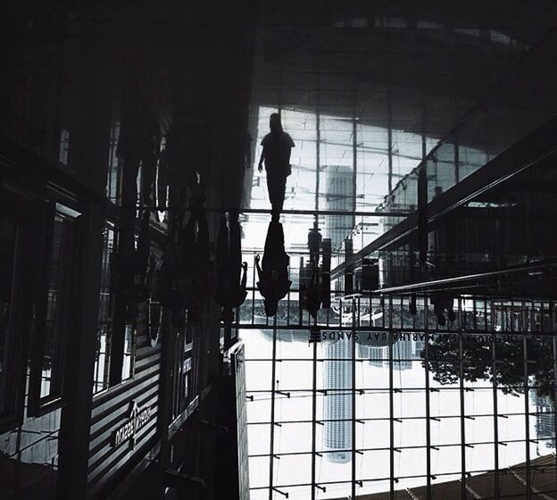 indoors, silhouette, architecture, built structure, window, men, lifestyles, full length, glass - material, standing, ceiling, reflection, walking, rear view, illuminated, railing, person, transparent