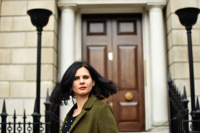 Portrait of woman with tousled hair standing against house