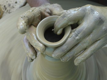 Cropped hands of potter shaping clay