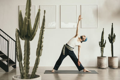 Full length of man standing by potted plant against wall