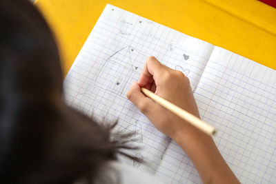 Girl drawing on book at table