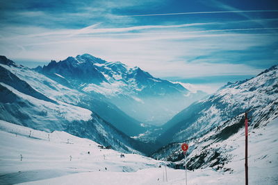 Scenic view of snowcapped mountains against cloudy sky