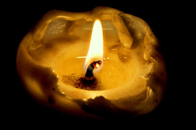 Close-up of lit candle against black background