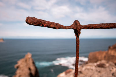 Close-up of rusty metal on beach against sky