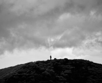 Low angle view of silhouette person standing on mountain against sky