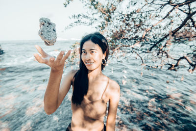 Portrait of shirtless man standing against sea