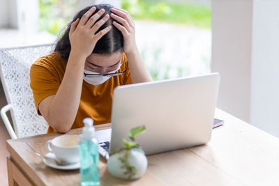 Midsection of woman using phone while sitting on table