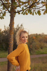 Portrait of woman standing by tree against plants