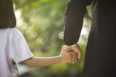 Cropped image of father and daughter holding hands