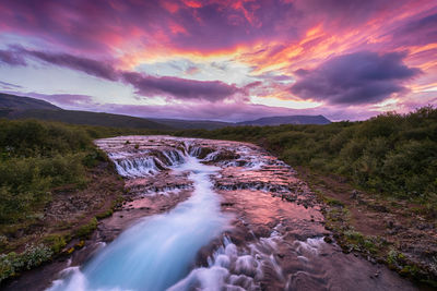 Scenic view of waterfall against sky during sunset