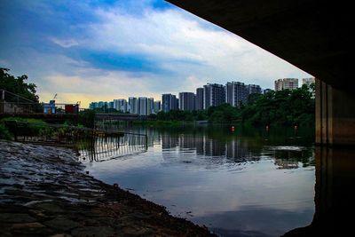 View of city at waterfront against cloudy sky