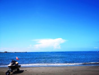 Scenic view of jet boat on beach against blue sky