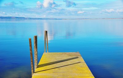 Wooden posts in lake against sky