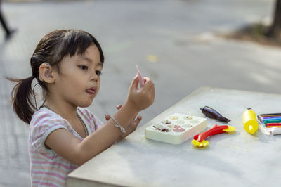Close-up of cute girl playing with childs play clay at table outdoors