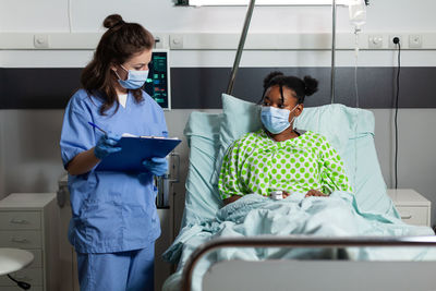 Nurse wearing mask while examining patient at hospital